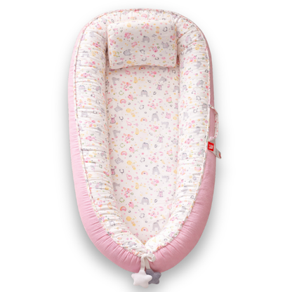 Pink baby lounger with white interior featuring pastel animal and floral print, viewed from above.