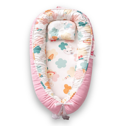Pink baby lounger with colorful animal and clover print on white interior, viewed from above.