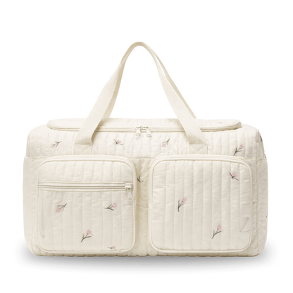 Cream-colored diaper bag with delicate pink floral design and two zippered front pockets.
