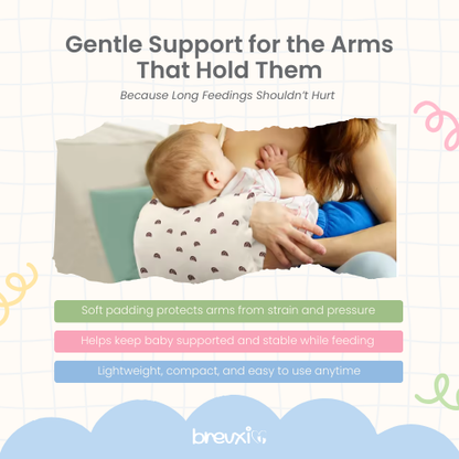 Woman breastfeeding while using a cream nursing pillow with brown rainbow pattern on her arm.